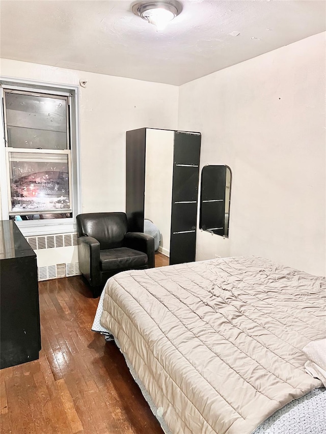 bedroom with wood-type flooring and radiator heating unit