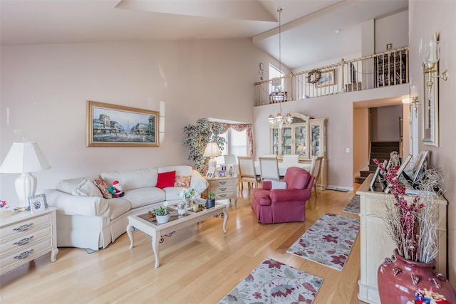 living room with light wood-type flooring, an inviting chandelier, and high vaulted ceiling