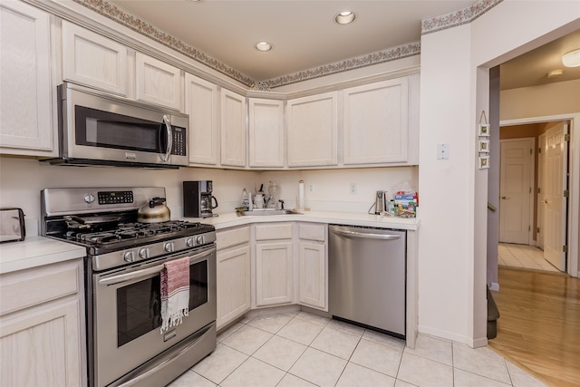 kitchen with appliances with stainless steel finishes, sink, and light tile patterned flooring