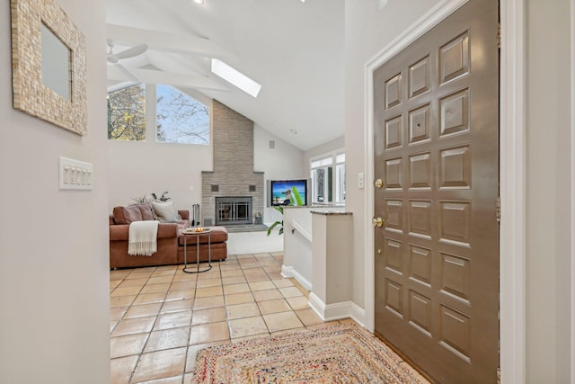 tiled foyer featuring a skylight, a wealth of natural light, a large fireplace, and ceiling fan