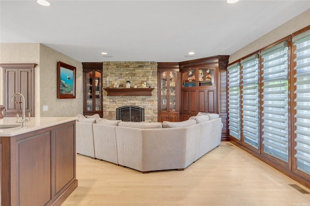 living room featuring sink, light wood-type flooring, and a fireplace