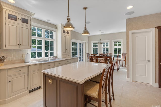 kitchen with cream cabinetry, pendant lighting, a kitchen island, and a healthy amount of sunlight