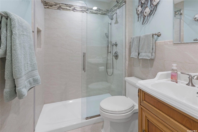 bathroom featuring walk in shower, vanity, toilet, and tile walls