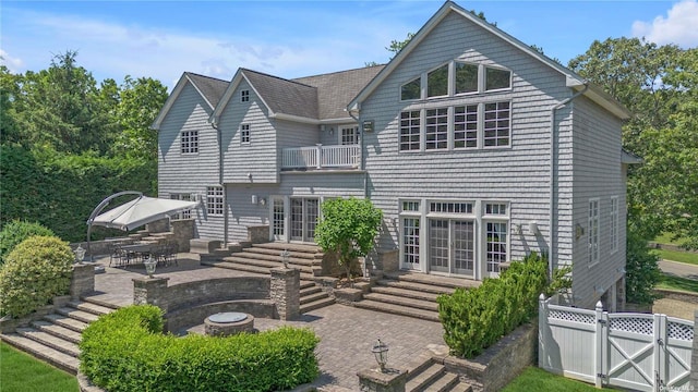 rear view of house with a balcony, a patio, and an outdoor fire pit