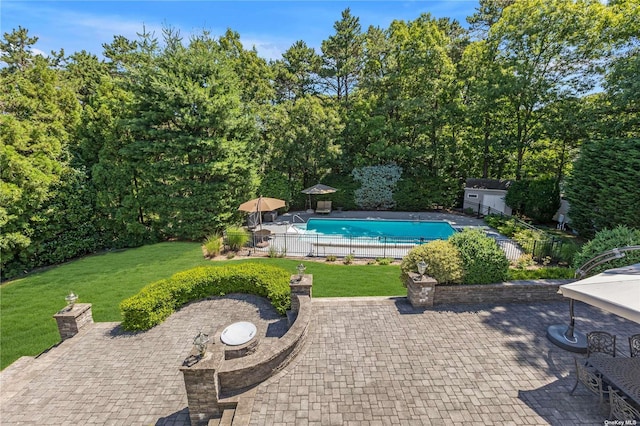 view of pool featuring a lawn, a patio area, and a shed