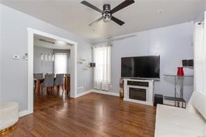 living room featuring ceiling fan, dark hardwood / wood-style flooring, and a fireplace