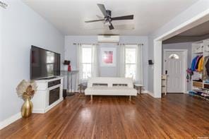 living room with a wall mounted AC, ceiling fan, and dark hardwood / wood-style floors