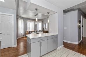 kitchen featuring kitchen peninsula, light hardwood / wood-style floors, gray cabinets, and hanging light fixtures