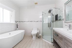 full bathroom featuring plus walk in shower, vanity, toilet, and tile walls