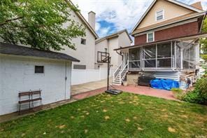 rear view of property featuring a lawn and a sunroom