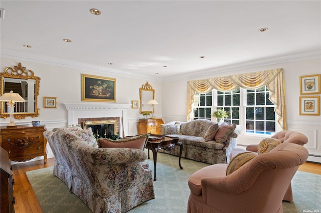 living room featuring a baseboard heating unit, light wood-type flooring, a fireplace, and ornamental molding