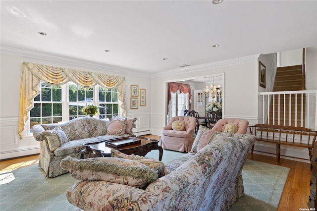 living room featuring baseboard heating, wood-type flooring, a notable chandelier, and ornamental molding