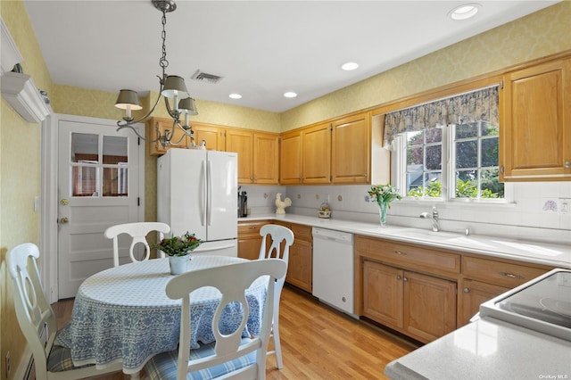 kitchen with pendant lighting, white appliances, sink, light hardwood / wood-style flooring, and a chandelier