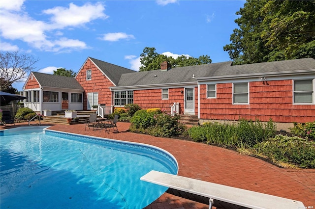 view of swimming pool featuring a patio area, a diving board, and a sunroom