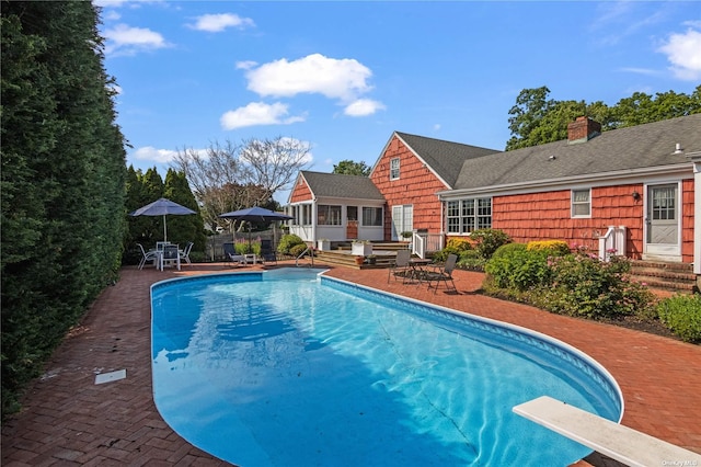 view of swimming pool with a patio area and a diving board