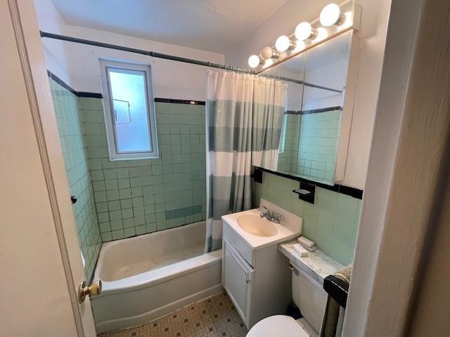 full bathroom with vanity, toilet, shower / bath combination with curtain, and tile walls