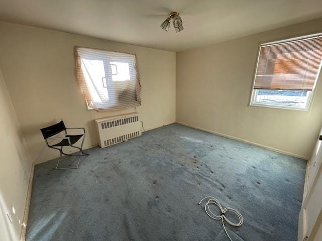 carpeted empty room featuring radiator heating unit