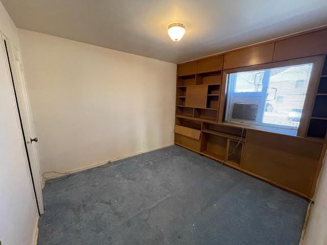 unfurnished living room with dark carpet and built in features