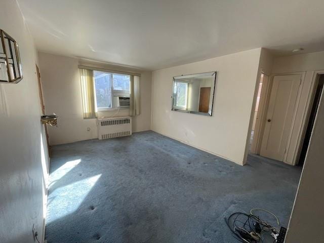 unfurnished living room with cooling unit, radiator, and carpet floors