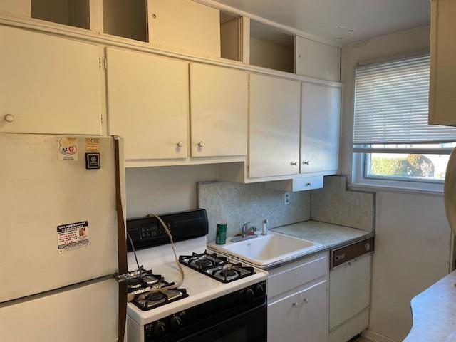 kitchen with sink, white cabinets, and white appliances