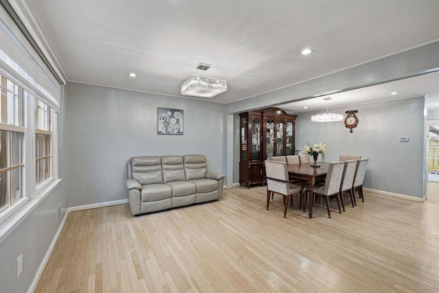 dining space with light hardwood / wood-style floors and a notable chandelier