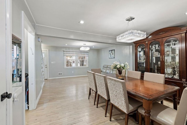 dining space with light wood-type flooring and an inviting chandelier