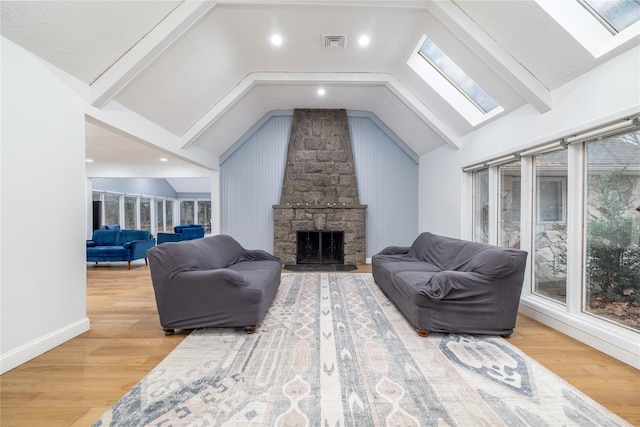 living room featuring a fireplace, wood-type flooring, and vaulted ceiling with skylight