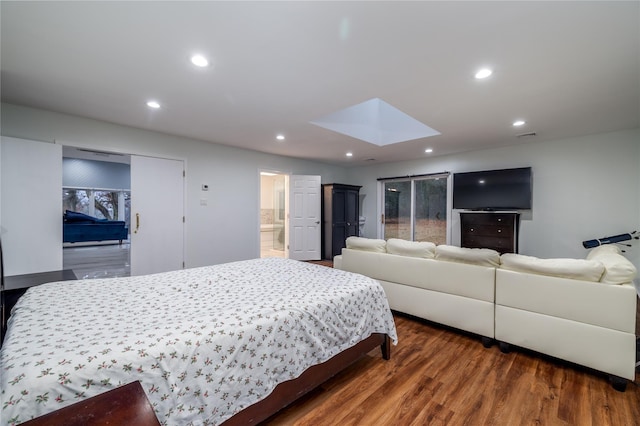 bedroom with connected bathroom, a skylight, and dark hardwood / wood-style flooring