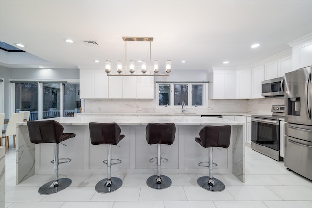 kitchen featuring white cabinets, a center island, hanging light fixtures, and appliances with stainless steel finishes