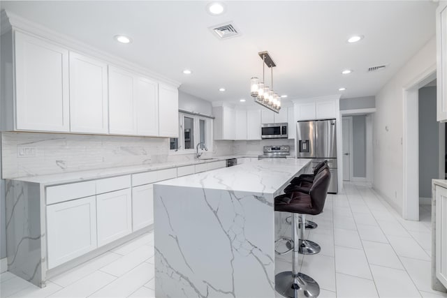 kitchen with white cabinetry, a center island, sink, hanging light fixtures, and appliances with stainless steel finishes