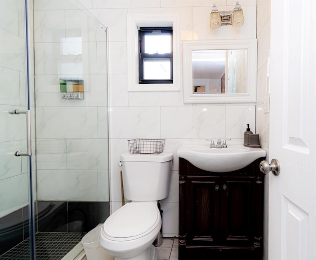 bathroom with vanity, toilet, tile walls, and a shower with shower door