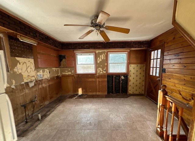 misc room featuring ceiling fan and wooden walls