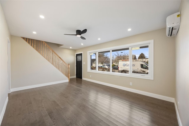 unfurnished living room with an AC wall unit, ceiling fan, and dark wood-type flooring