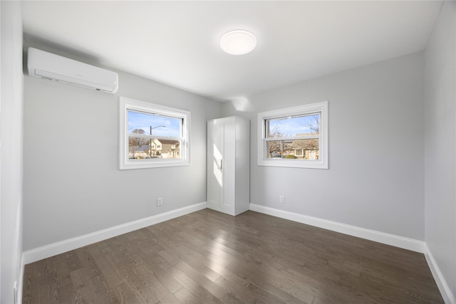 unfurnished bedroom featuring dark hardwood / wood-style floors, a wall unit AC, and multiple windows