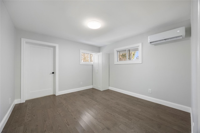 empty room with dark hardwood / wood-style flooring and a wall unit AC