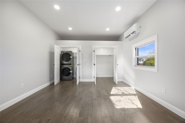 unfurnished bedroom featuring a wall mounted air conditioner, stacked washer / drying machine, and dark hardwood / wood-style floors