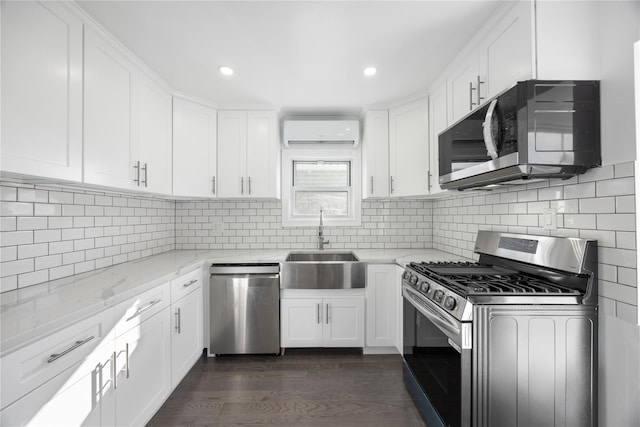 kitchen featuring a wall mounted air conditioner, appliances with stainless steel finishes, white cabinets, and light stone counters