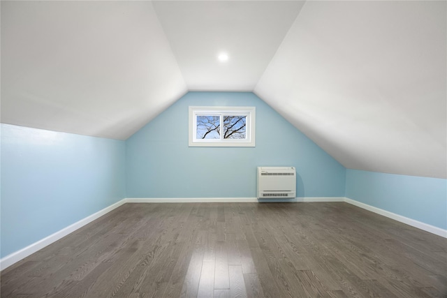 additional living space featuring heating unit, dark hardwood / wood-style floors, and lofted ceiling