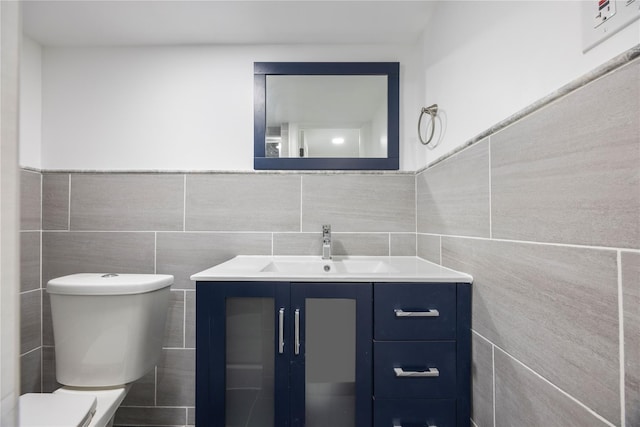 bathroom featuring vanity, toilet, and tile walls