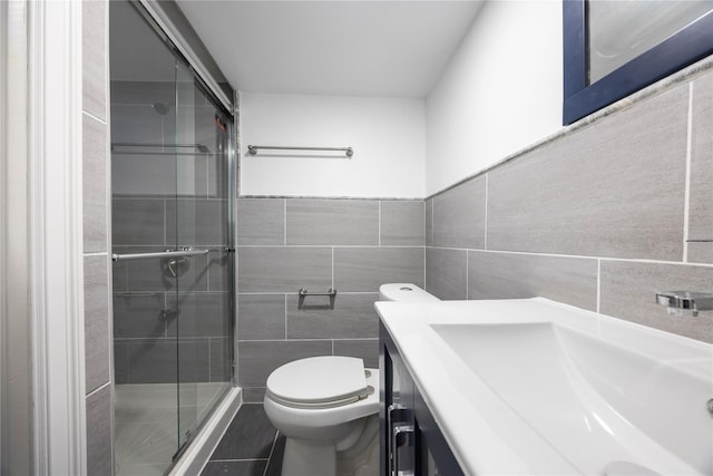 bathroom featuring vanity, tile patterned floors, toilet, tile walls, and a shower with shower door