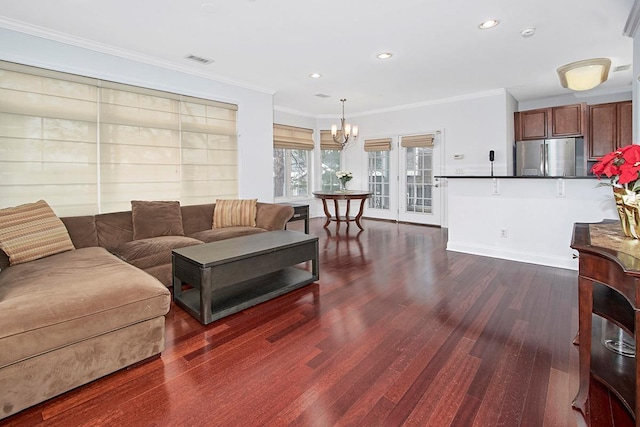 living room with crown molding, dark hardwood / wood-style flooring, and an inviting chandelier