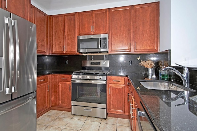 kitchen with sink, tasteful backsplash, dark stone counters, light tile patterned floors, and appliances with stainless steel finishes