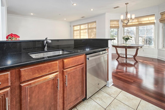 kitchen featuring stainless steel dishwasher, a wealth of natural light, sink, light tile patterned floors, and a notable chandelier