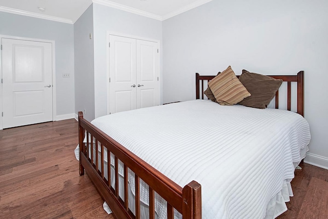 bedroom with dark hardwood / wood-style flooring, crown molding, and a closet