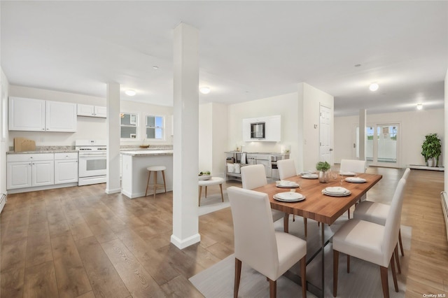 dining space featuring light hardwood / wood-style floors, a wealth of natural light, and a baseboard radiator