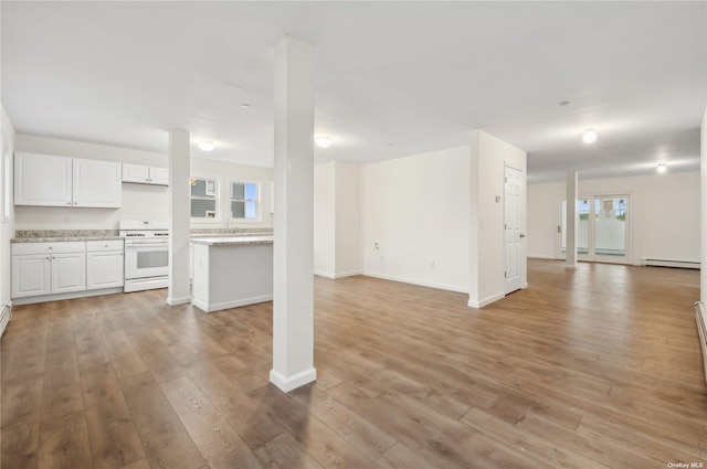 unfurnished living room featuring a healthy amount of sunlight, baseboard heating, and light hardwood / wood-style flooring