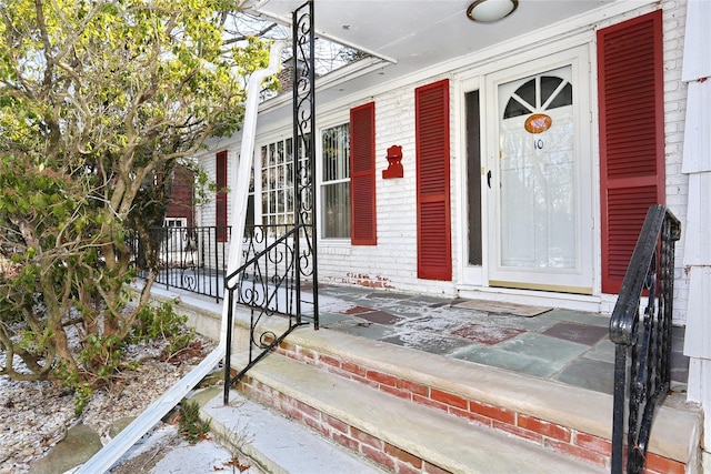 view of exterior entry with brick siding and covered porch