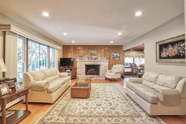 living area featuring wooden walls, recessed lighting, a fireplace, and light wood-type flooring