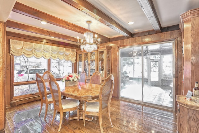 dining space with a notable chandelier, wooden walls, and hardwood / wood-style floors