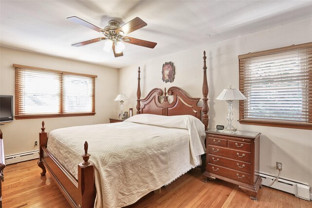 bedroom with a baseboard heating unit, ceiling fan, and wood finished floors